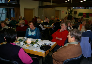 Foto: Seniorinnen sitzen am Tisch, essen Kuchen, lachen und unterhalten sich.